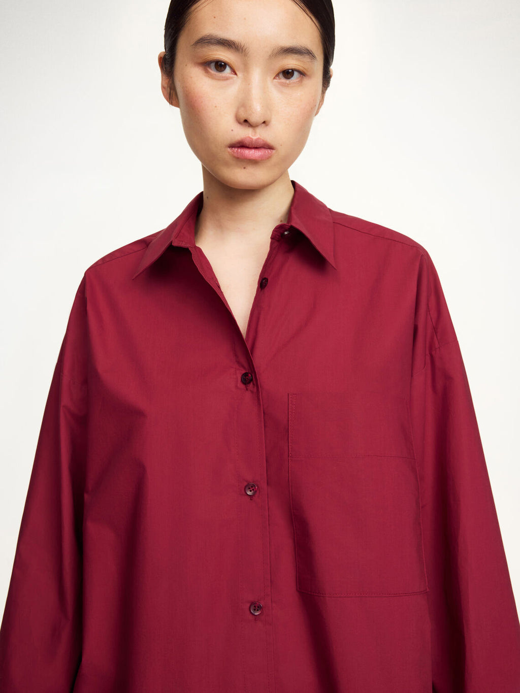By Malene Birger Derris oversized burgunder skjorte, detalj av brystlomme og knapperekke.