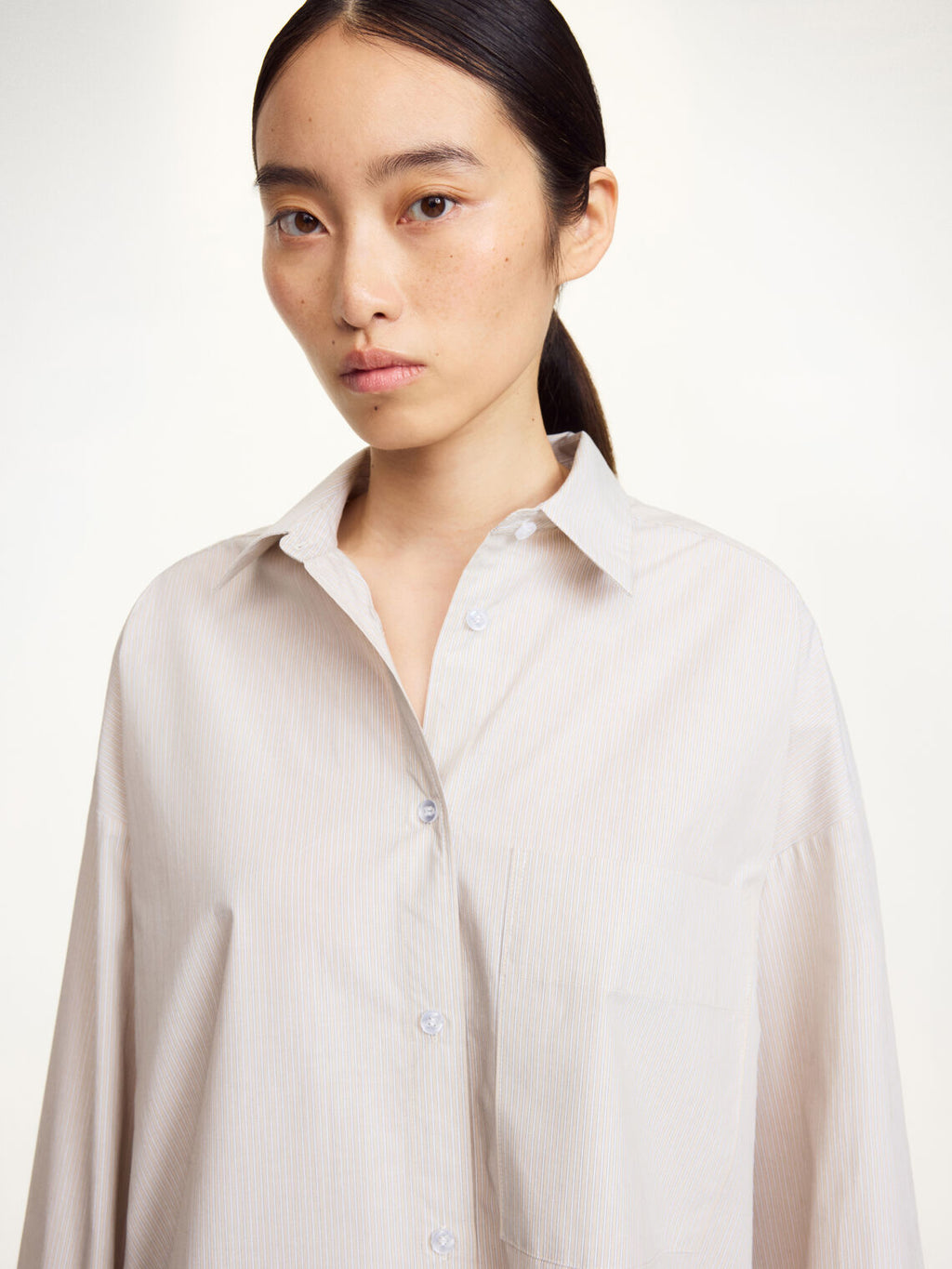 By Malene Birger Derris oversized beige skjorte, detalj av brystlomme og knapperekke.