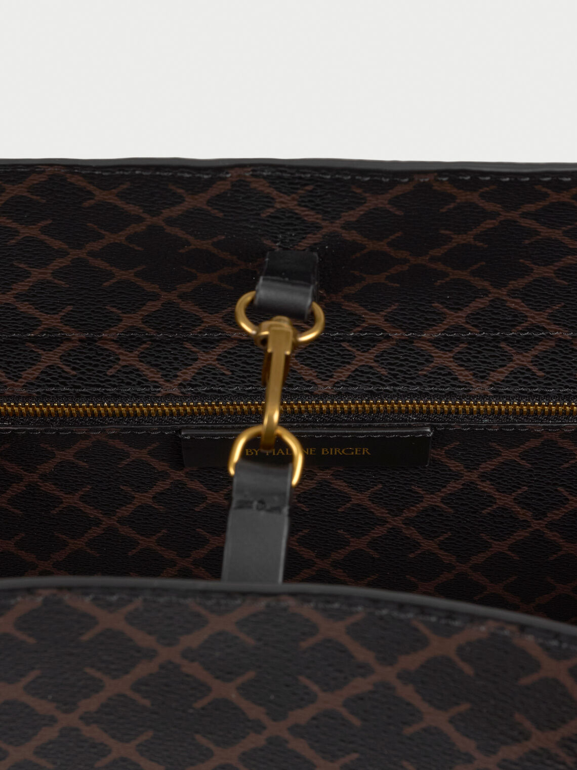 ABI TOTE veske fra By Malene Birger i fargen brun, laget i polyvinylklorid med Signature Flower print og skinnhåndtak. Romslig modell med innvendig lomme.