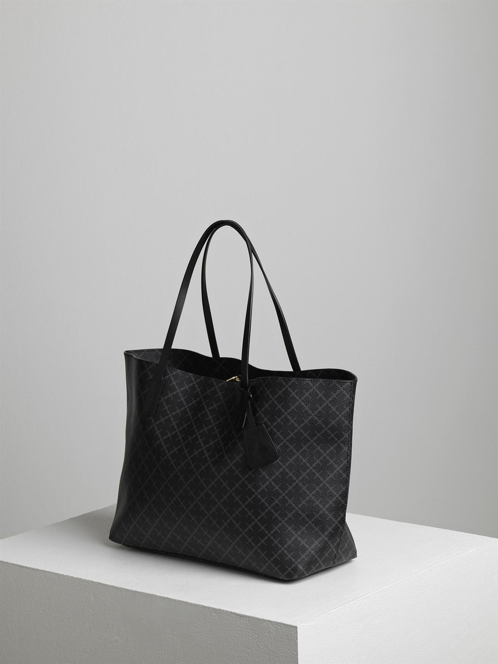 By Malene Birger Abigail veske i koksgrå, med Signature Flower-print og skinndetaljer, laget av polyvinylklorid.