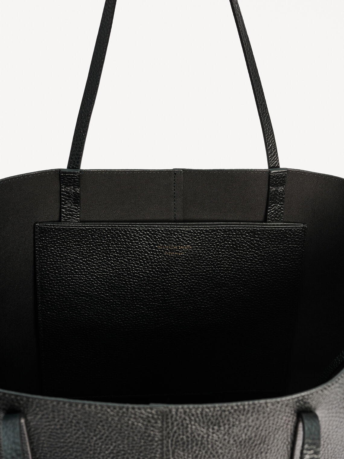 By Malene Birger Abilla skinnveske i sort kuskinn, med strukturert overflate, en romslig størrelse og to skinnreimer for lukking.