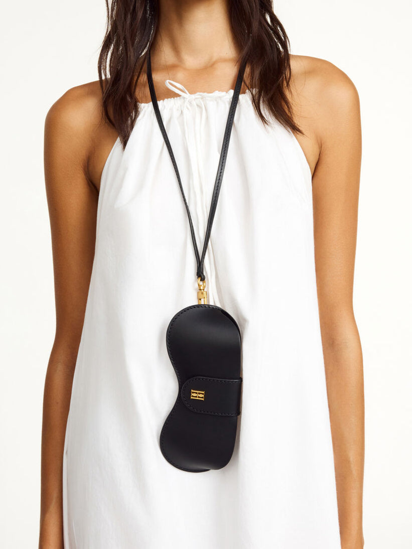 By Malene Birger Aya Sunny solbrilleetui i sort kuskinn, med monogram-logo i front og en avtagbar reim.
