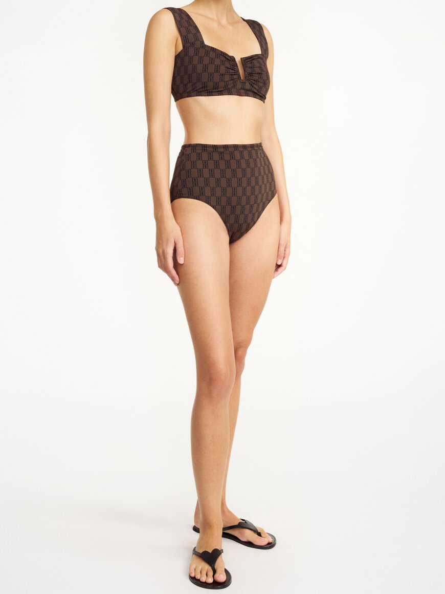 By Malene Birger Belira bikinitruse i mørkebrun, laget av resirkulert polyamid og elastan, med høyt liv og monogramprint.