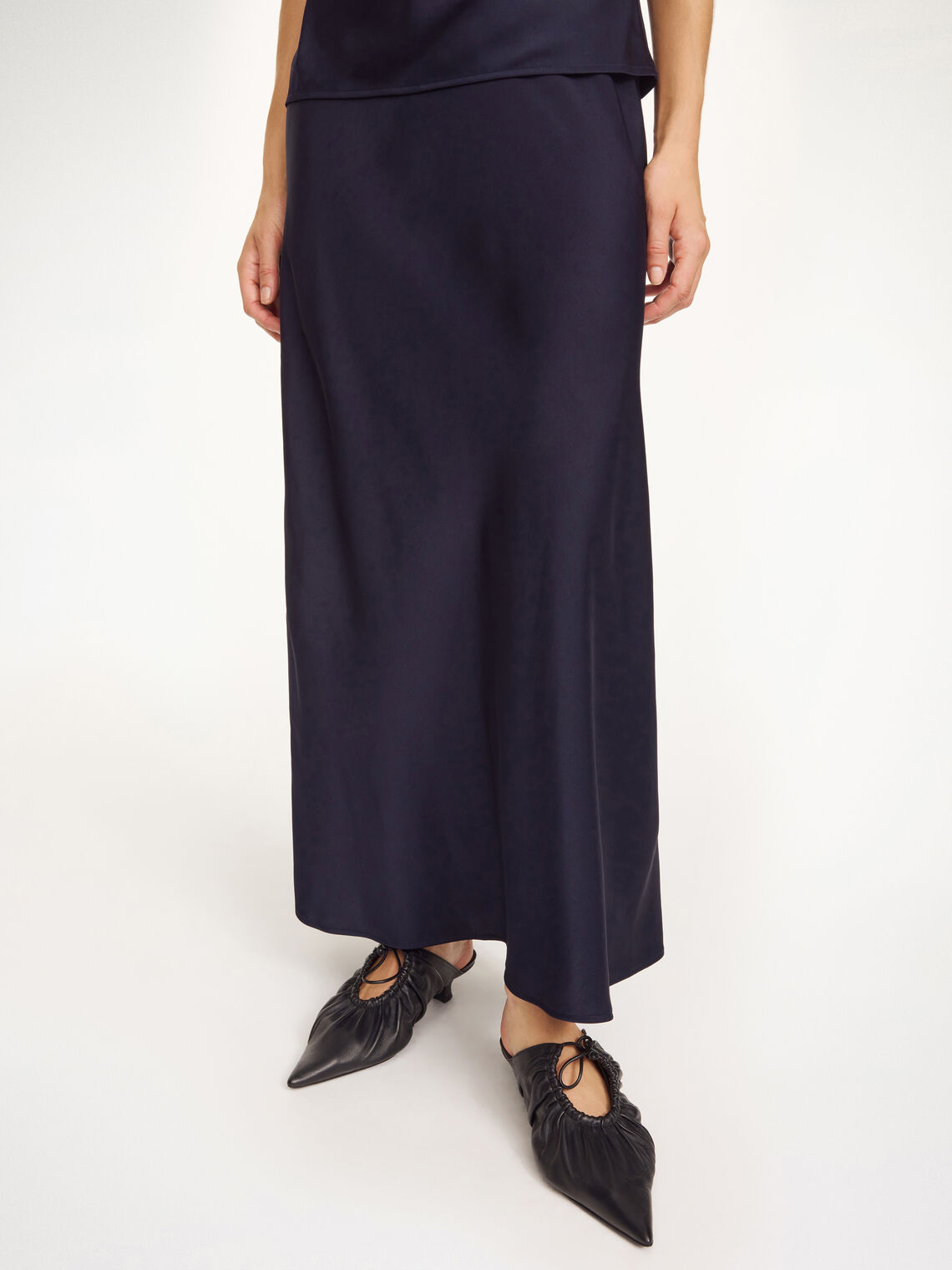 By Malene Birger Boshan satengskjørt i mørkeblå, detalj av asymmetrisk hem i Naia-acetat og polyester.