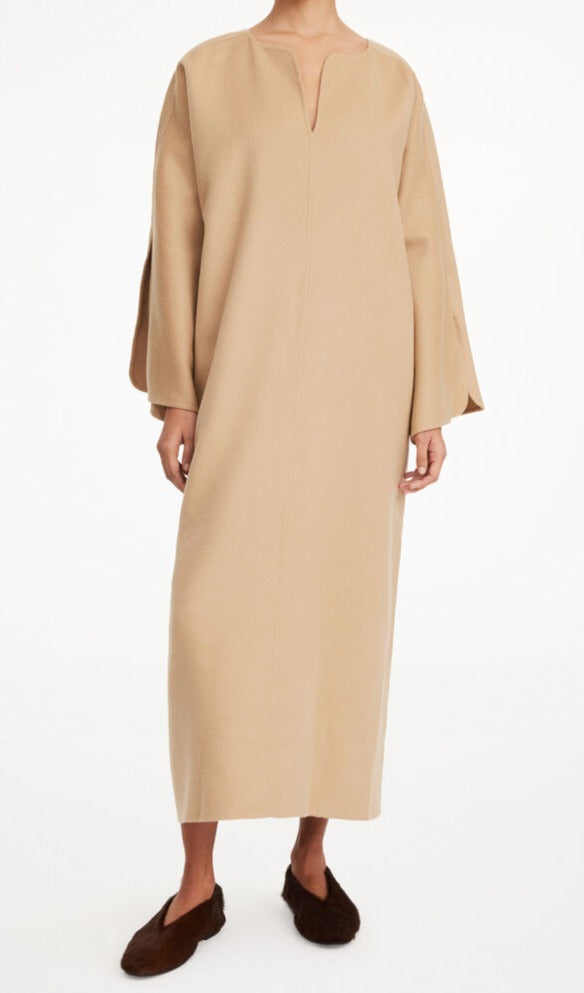 By Malene Birger Cais kjole i beige, laget av 100% ull, med en løs passform, v-utringning og splitt på ermene.