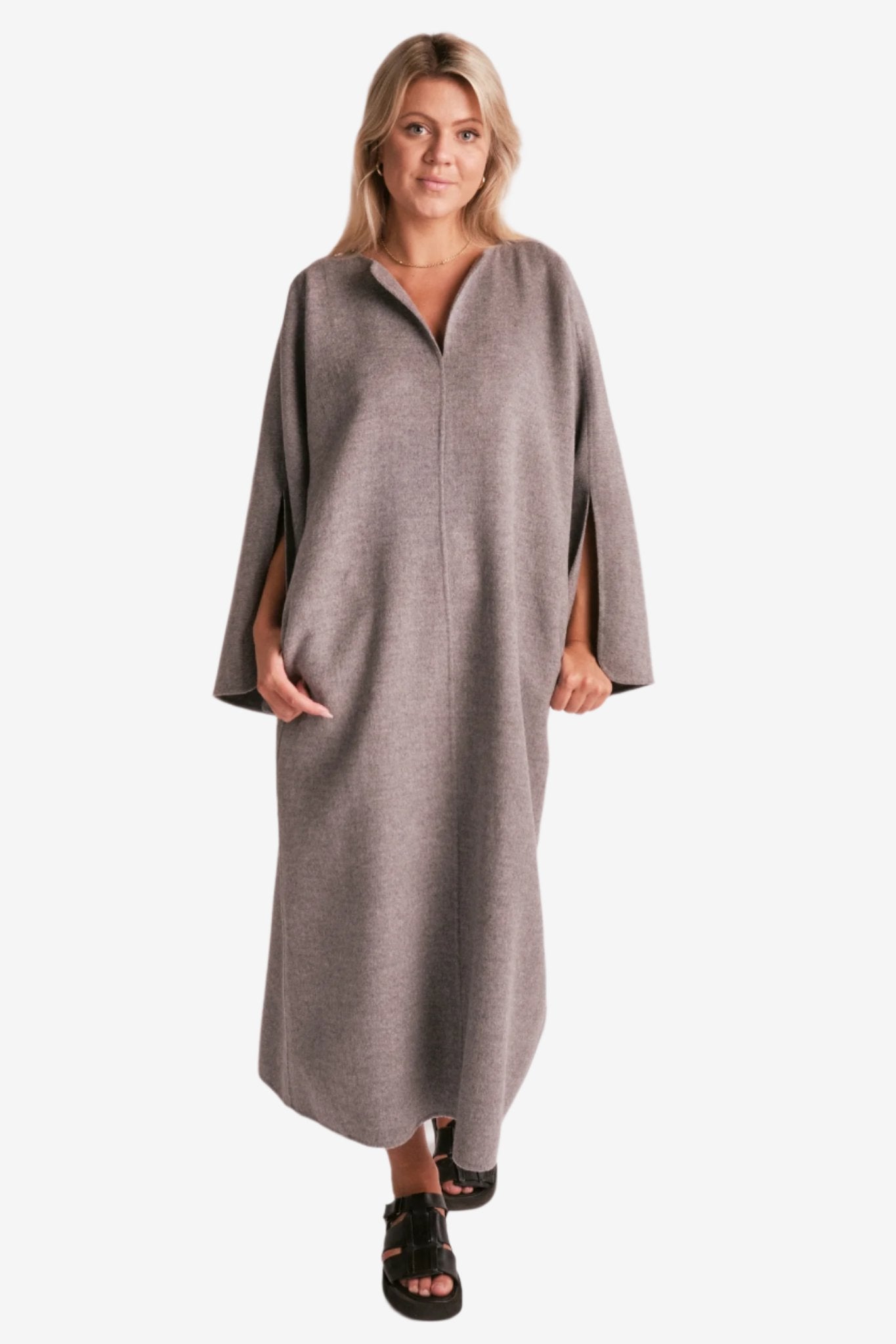 By Malene Birger Cais kjole i grått, laget av 100% ull, med en løs passform, v-utringning og splitt på ermene.