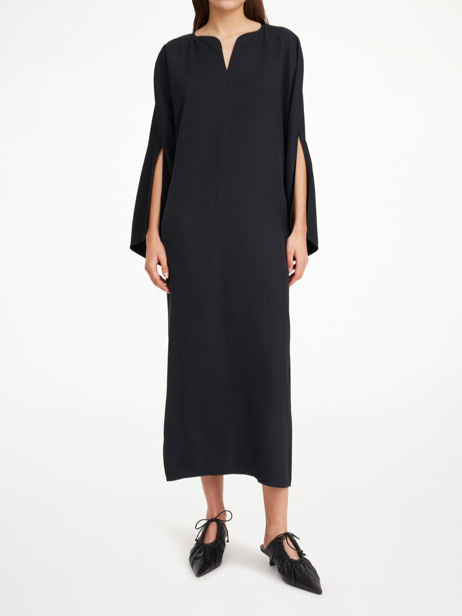 By Malene Birger Cais kjole i sort, laget av lett acetat, med ankel lang lengde, nett v-utringing og splitt på ermene.