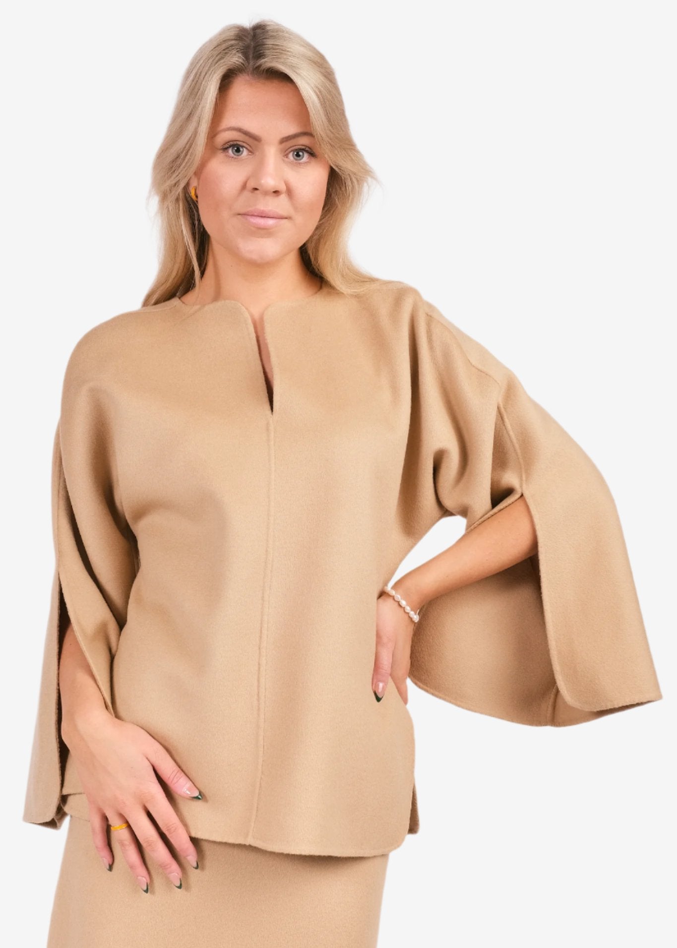 By Malene Birger Calias bluse i beige, med v-utringning og splitt på ermene, laget av 100% ull.