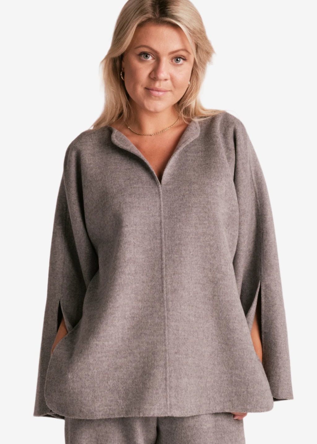 By Malene Birger Calias bluse i grå, laget av 100% ull, med v-utringning og splitt på ermene.