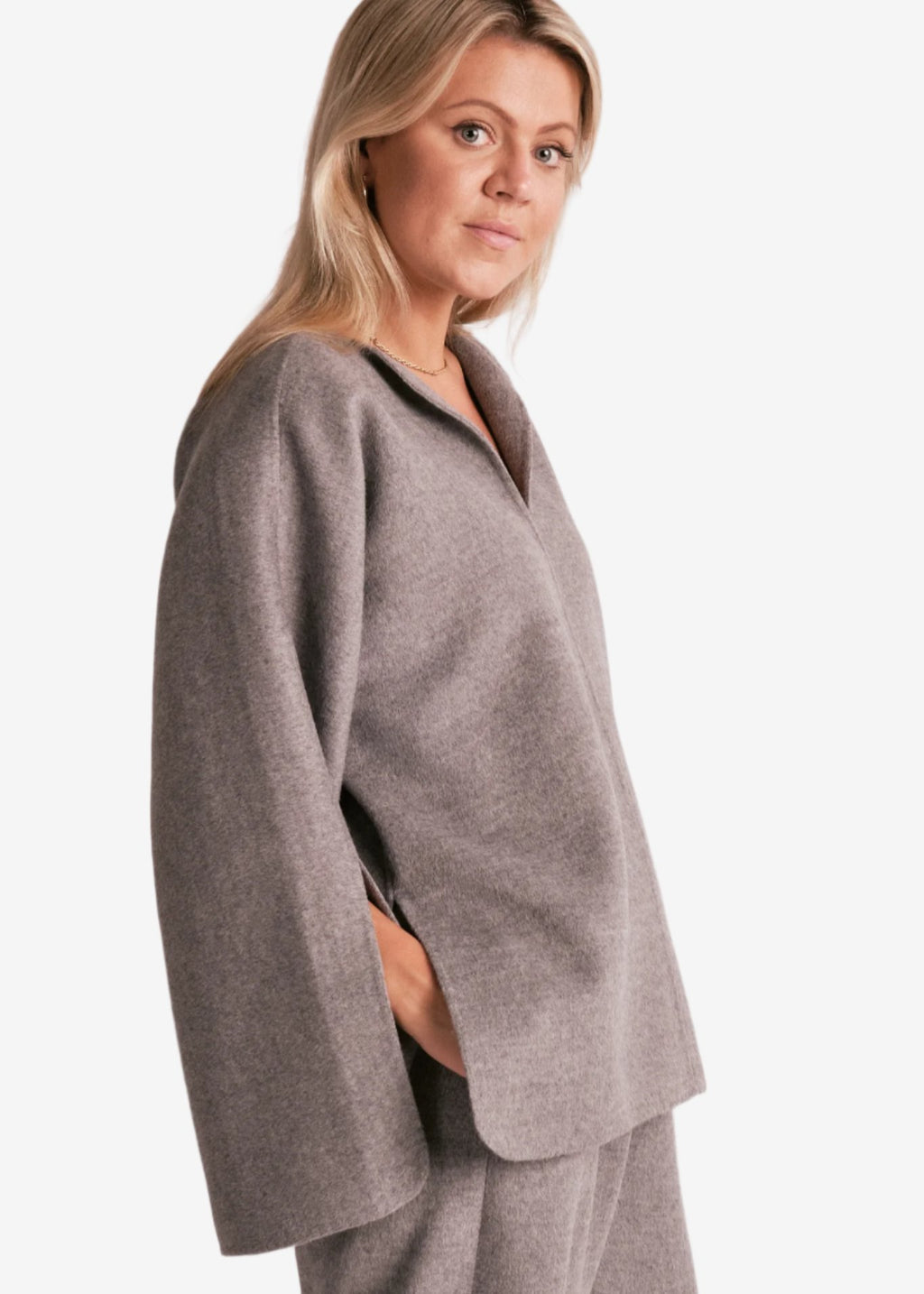 By Malene Birger Calias bluse i grå, laget av 100% ull, med v-utringning og splitt på ermene.