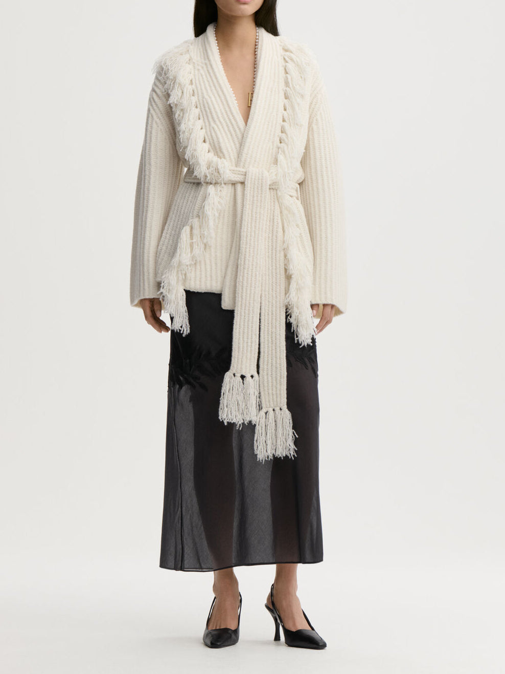 CANDELA cardigan fra By Malene Birger i fargen hvit, laget i 65% ull og 35% resirkulert polyamid. Ribbestrikk, frynser, lommer, noe oversized passform og avtagbart belte.