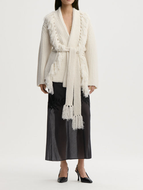 CANDELA cardigan fra By Malene Birger i fargen hvit, laget i 65% ull og 35% resirkulert polyamid. Ribbestrikk, frynser, lommer, noe oversized passform og avtagbart belte.