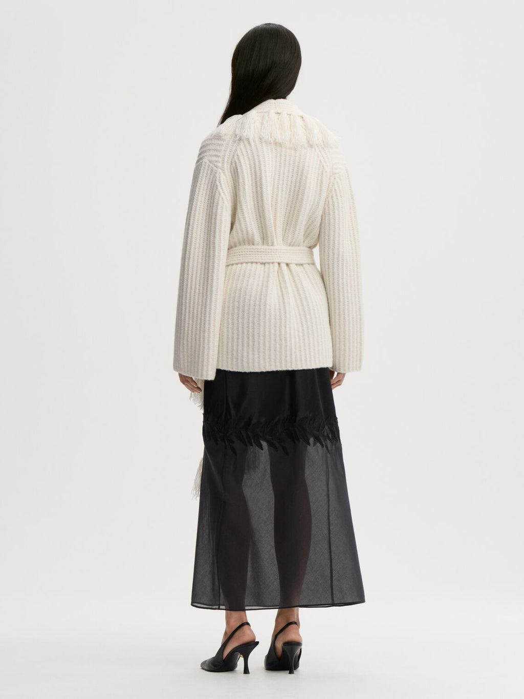 CANDELA cardigan fra By Malene Birger i fargen hvit, laget i 65% ull og 35% resirkulert polyamid. Ribbestrikk, frynser, lommer, noe oversized passform og avtagbart belte.