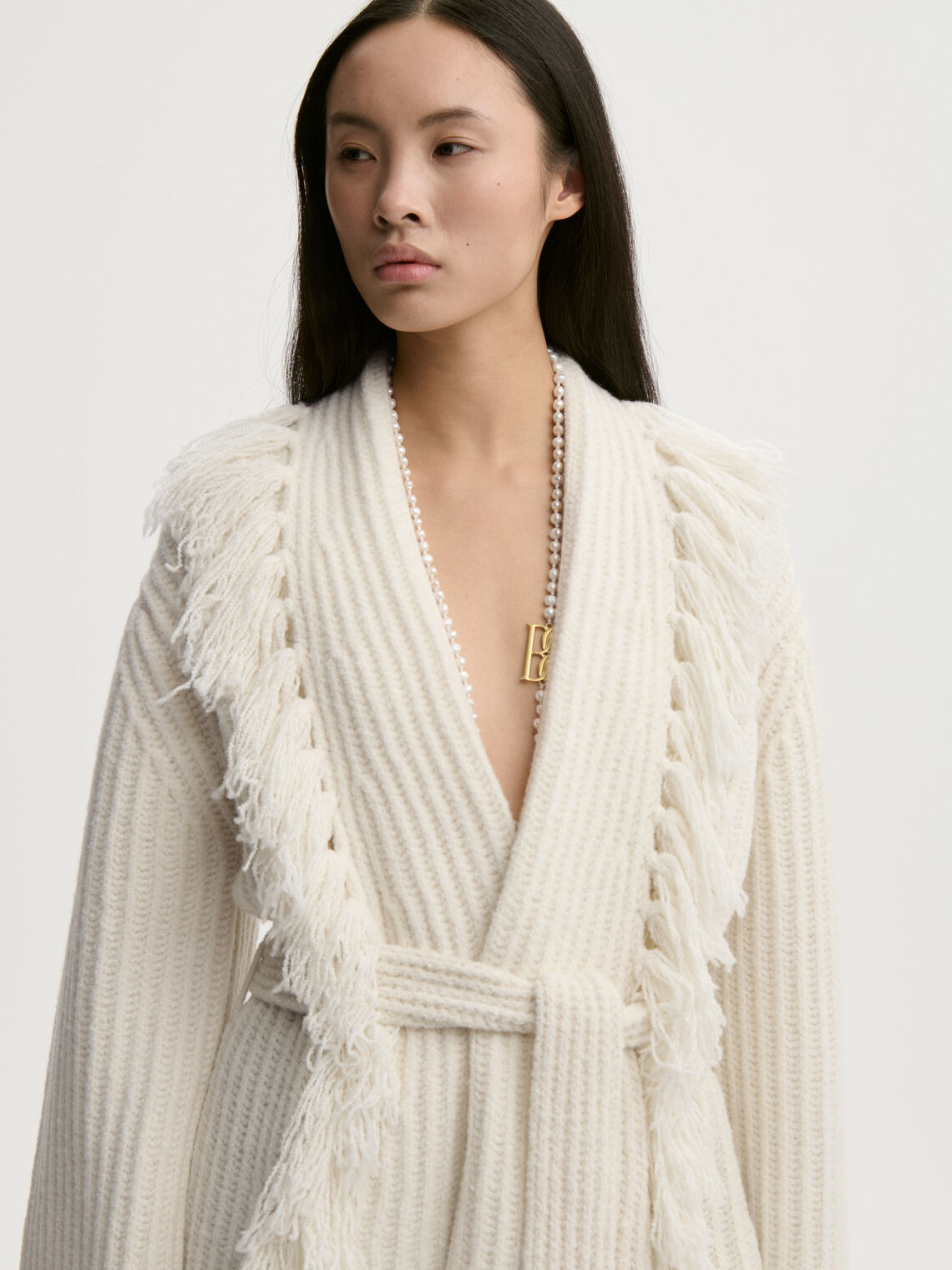 CANDELA cardigan fra By Malene Birger i fargen hvit, laget i 65% ull og 35% resirkulert polyamid. Ribbestrikk, frynser, lommer, noe oversized passform og avtagbart belte.