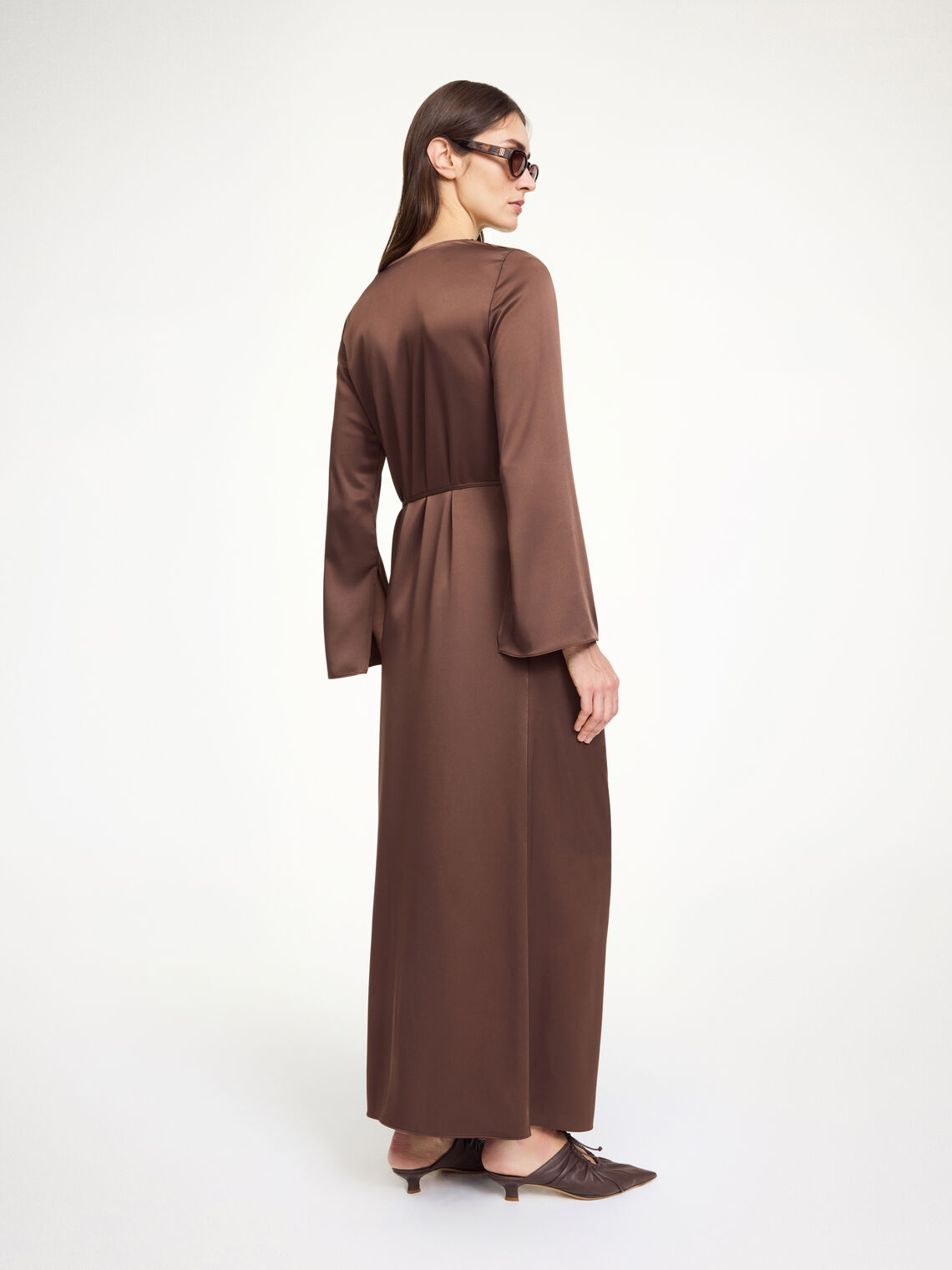 By Malene Birger Carrie lang kjole i mørkebrun, med drapert utringning, avtagbart belte og splitt i siden, laget av acetat og polyester.