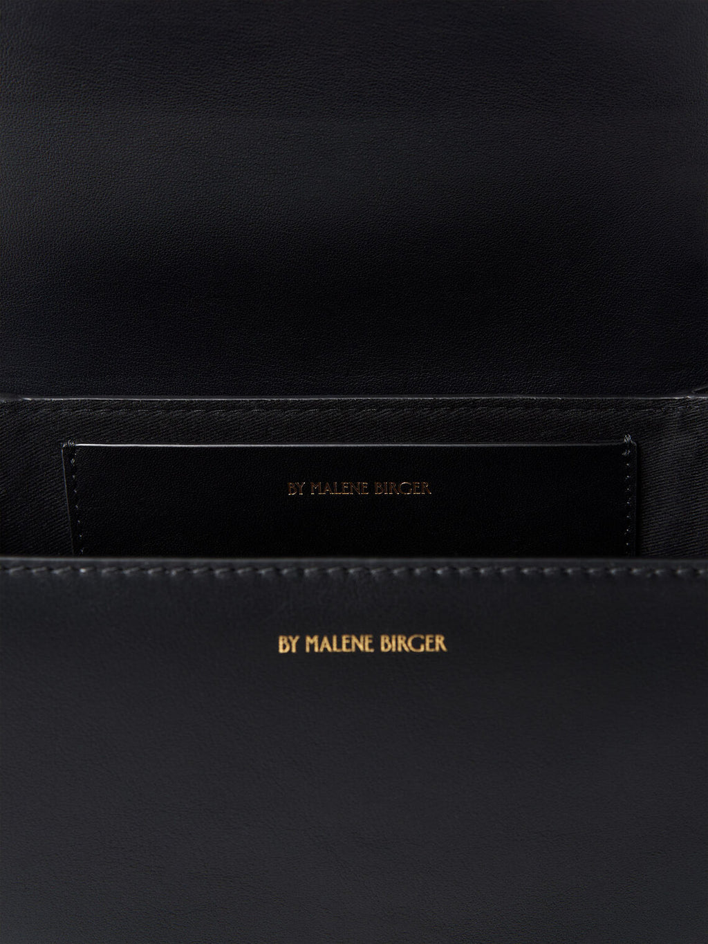 By Malene Birger Cebelle liten veske i sort kuskinn, med Swirl-motiv och justerbar axelrem.