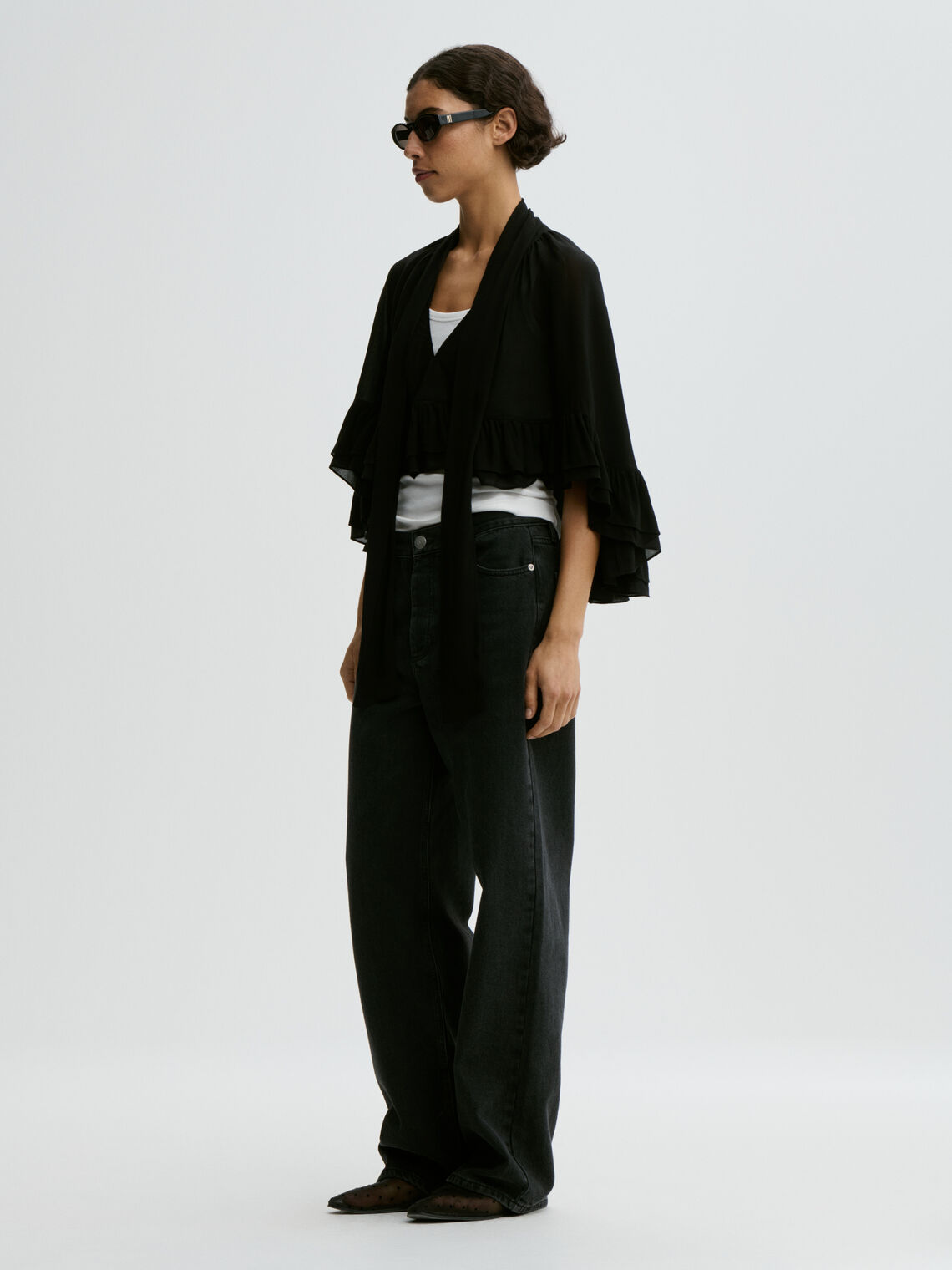 CEDI cape fra By Malene Birger i fargen sort, laget i viskose. Cropped lengde i front, v-utringing og justerbar knyting.