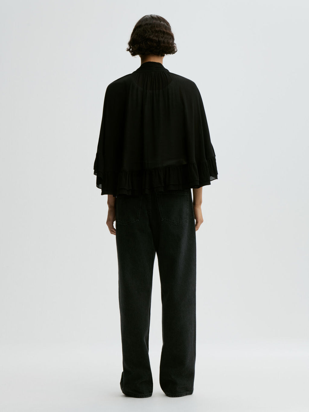 CEDI cape fra By Malene Birger i fargen sort, laget i viskose. Cropped lengde i front, v-utringing og justerbar knyting.