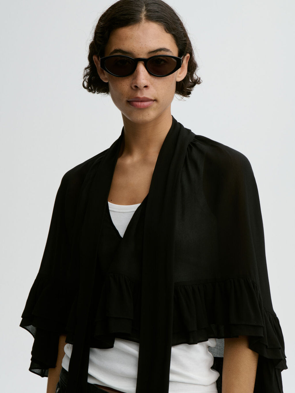 CEDI cape fra By Malene Birger i fargen sort, laget i viskose. Cropped lengde i front, v-utringing og justerbar knyting.