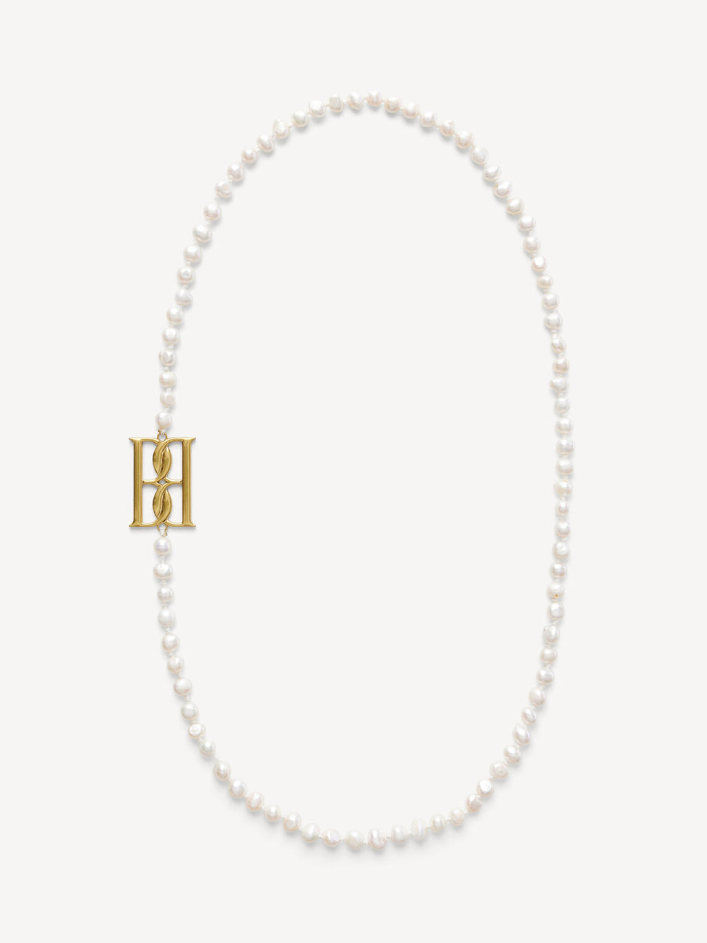 By Malene Birger Chakallo smykke i hvite ferskvannsperler med monogrambrosje, 89 cm langt.