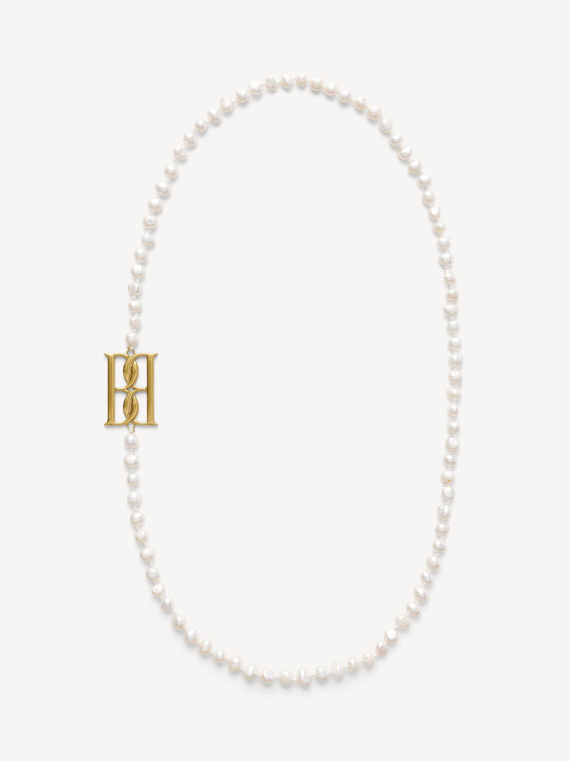 By Malene Birger Chakallo smykke i hvite ferskvannsperler med monogrambrosje, 89 cm langt.