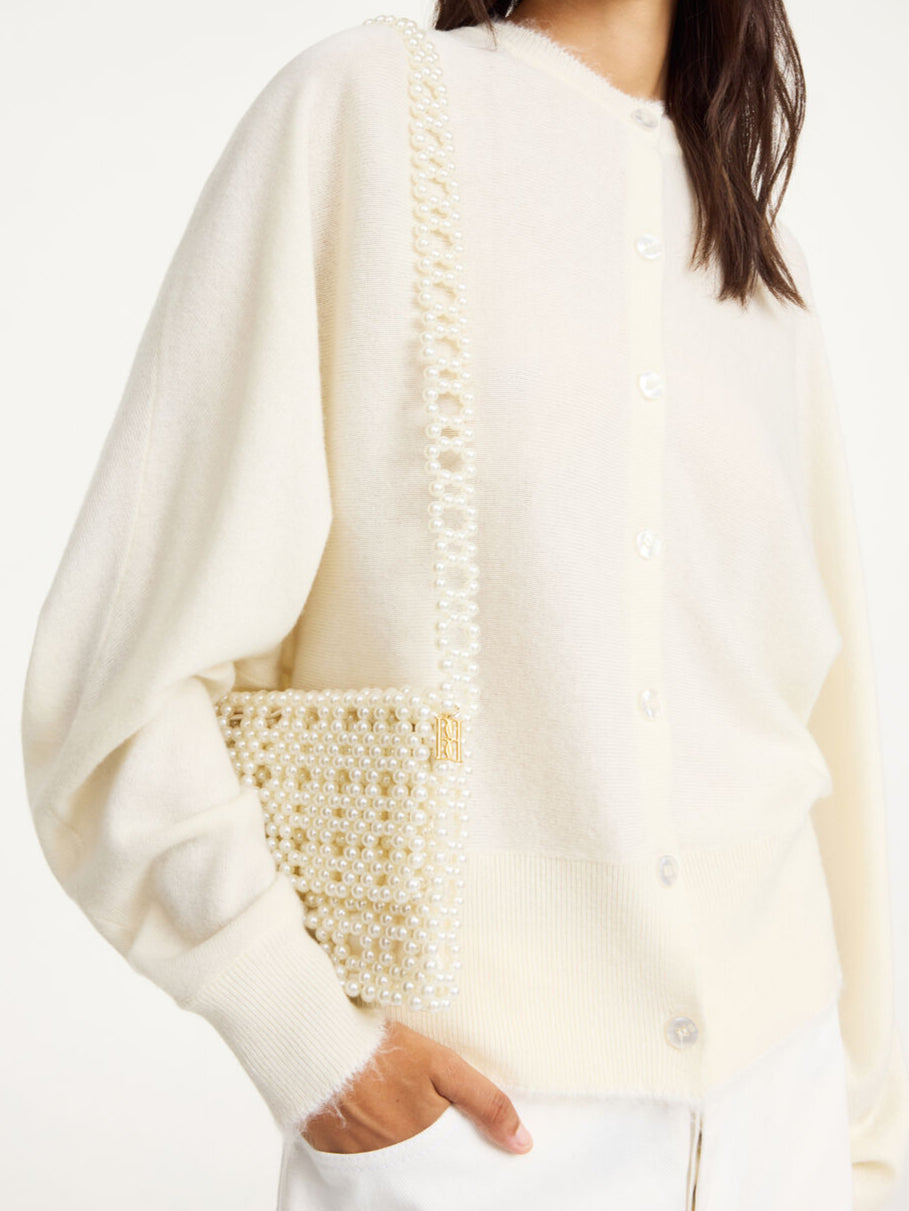 By Malene Birger Chaklo veske i hvit, med perler og monogram-detaljer på siden.

