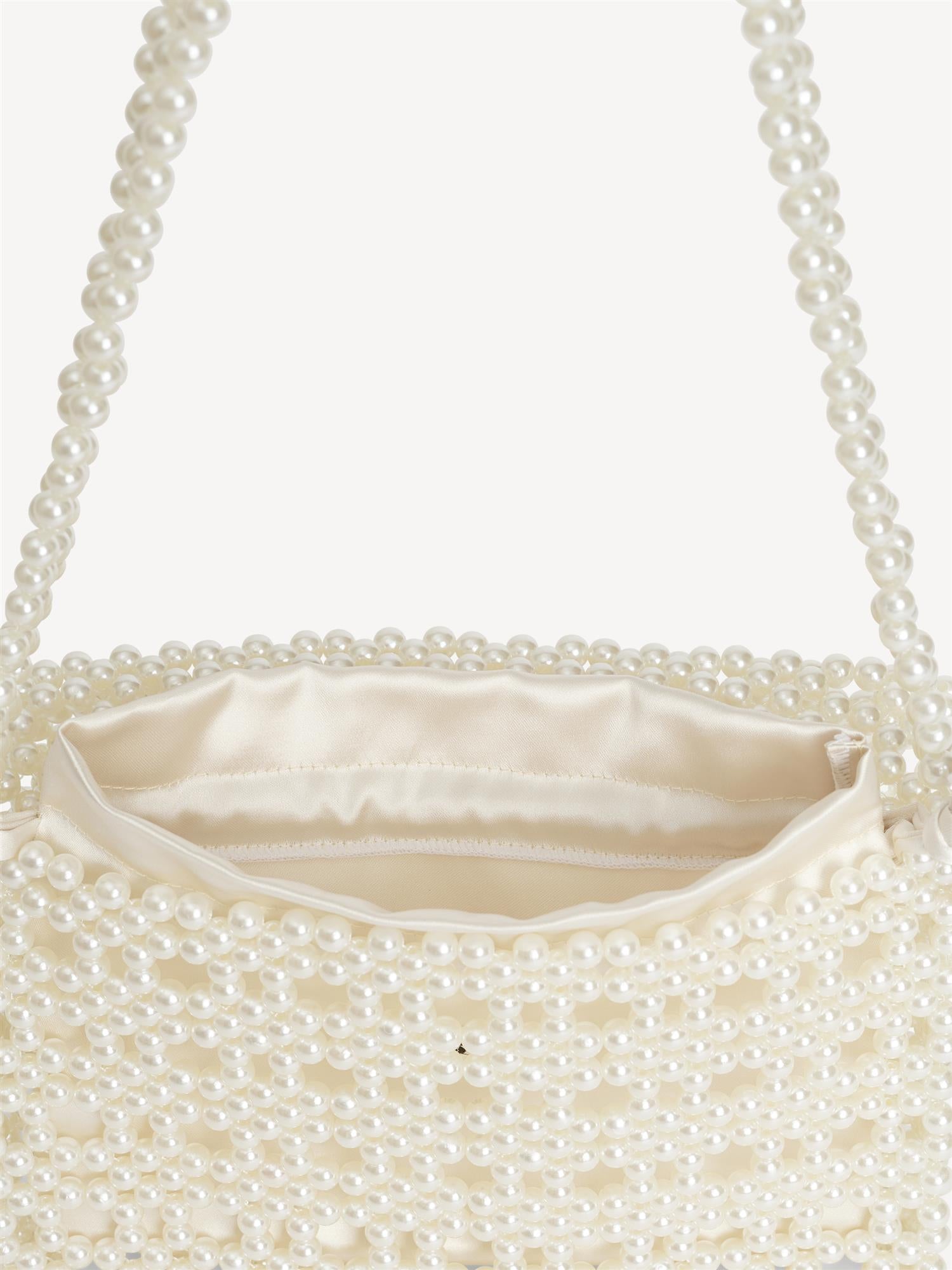 By Malene Birger Chaklo veske i hvit, med perler og monogram-detaljer på siden.

