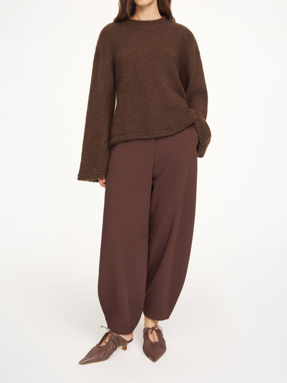 By Malene Birger Cierra genser i mørkebrun, med "flette-strikk" detaljer og trompetformede ermer, laget av ull, mohair og polyamid.