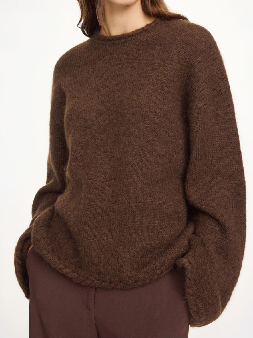 By Malene Birger Cierra genser i mørkebrun, med "flette-strikk" detaljer og trompetformede ermer, laget av ull, mohair og polyamid.