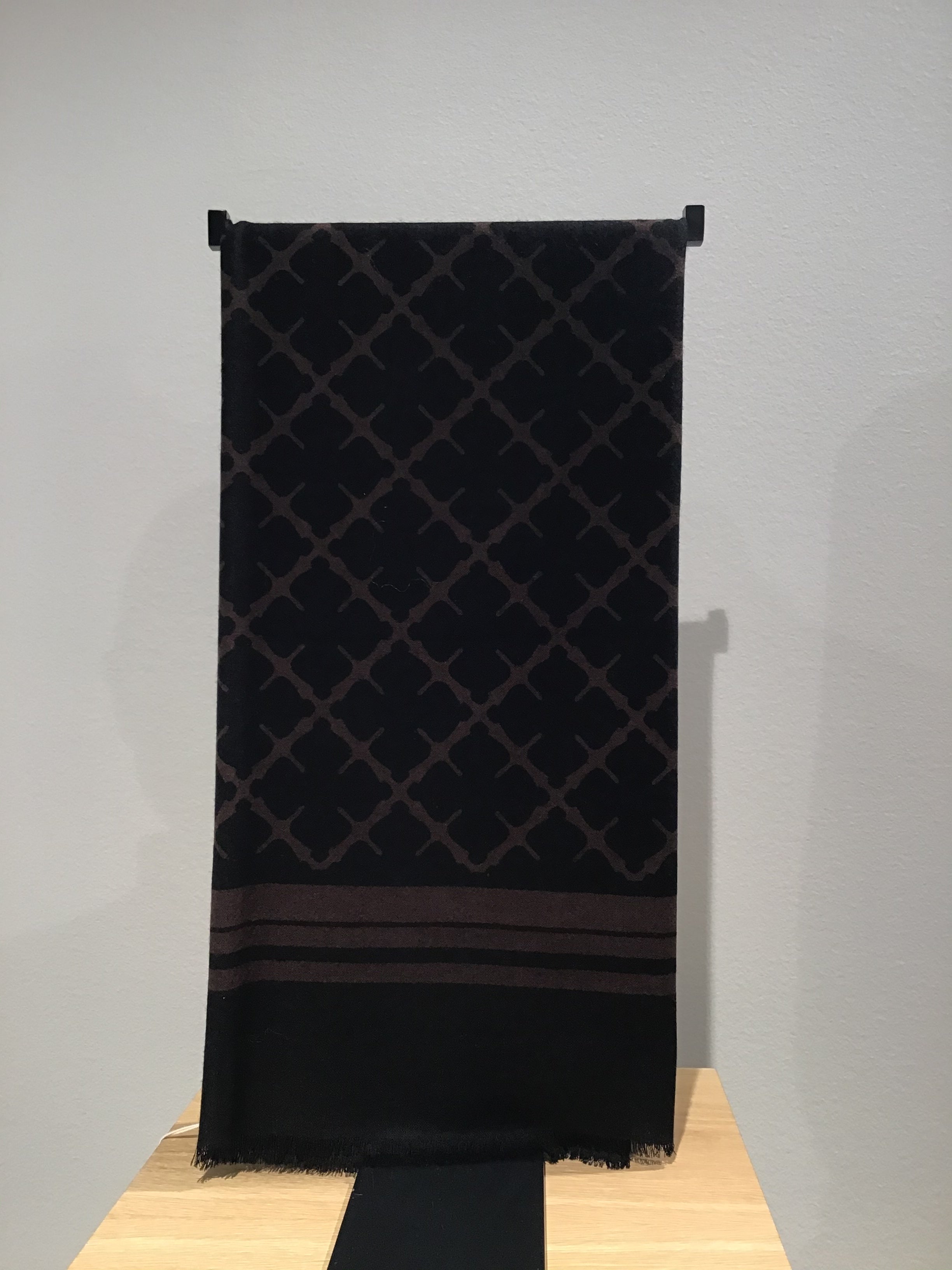 By Malene Birger Cornelis skjerf i mørkebrun, laget av 100% ull med Signature Flower-print og små frynser på sidene.