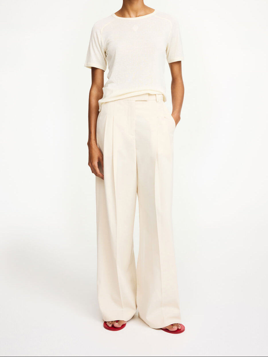 By Malene Birger Cymbria bukser i kremhvit, med en skreddersydd look, høyt liv og vide ben, laget av resirkulert polyester.