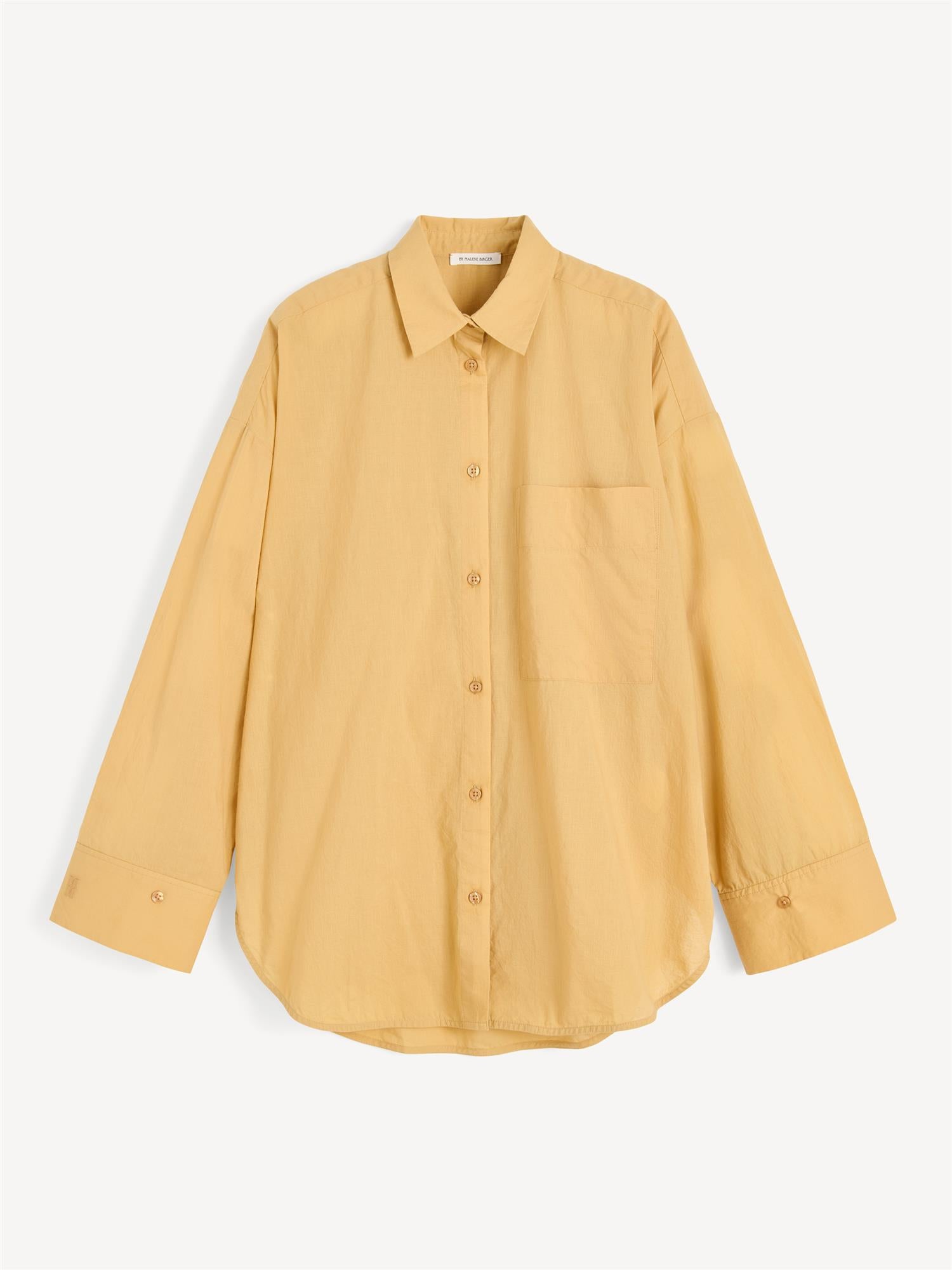 By Malene Birger Derris bomullskjorte i mørk gul, med en oversized passform og brystlomme, laget av 100% organisk bomull.