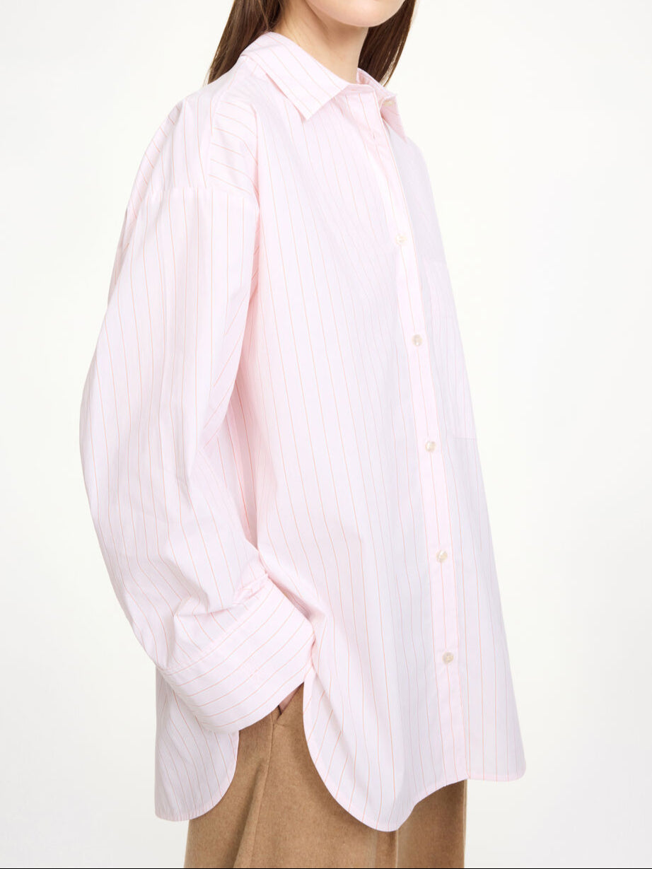 By Malene Birger Derris bomullskjorte i rosa, med tynne røde striper og en oversized passform, laget av 100% organisk bomull.