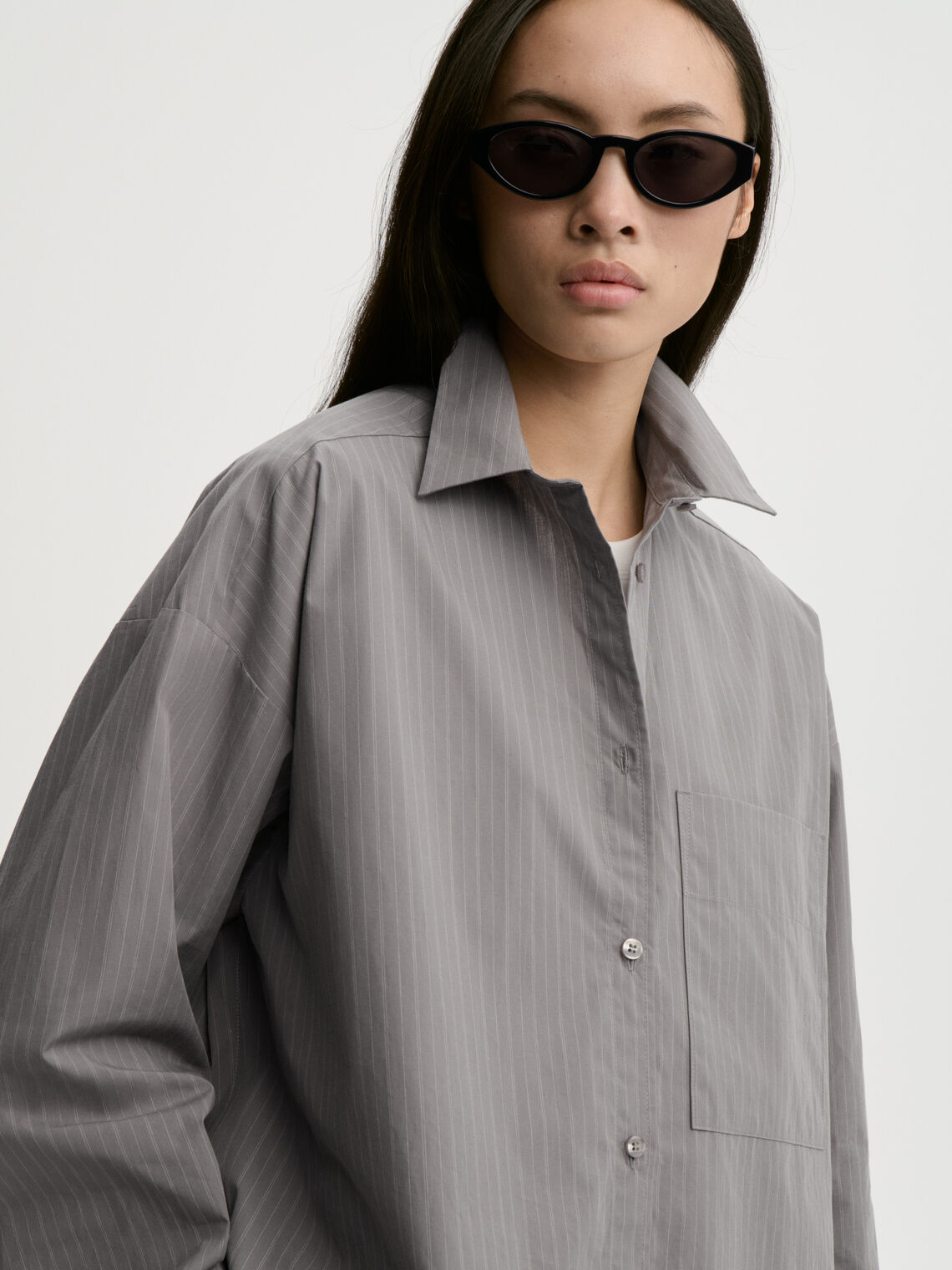 DERRIS bomullsskjorte fra By Malene Birger i fargen grå med hvite striper, laget i 100% organisk bomull. Oversized passform med knapper i front og brystlomme.
