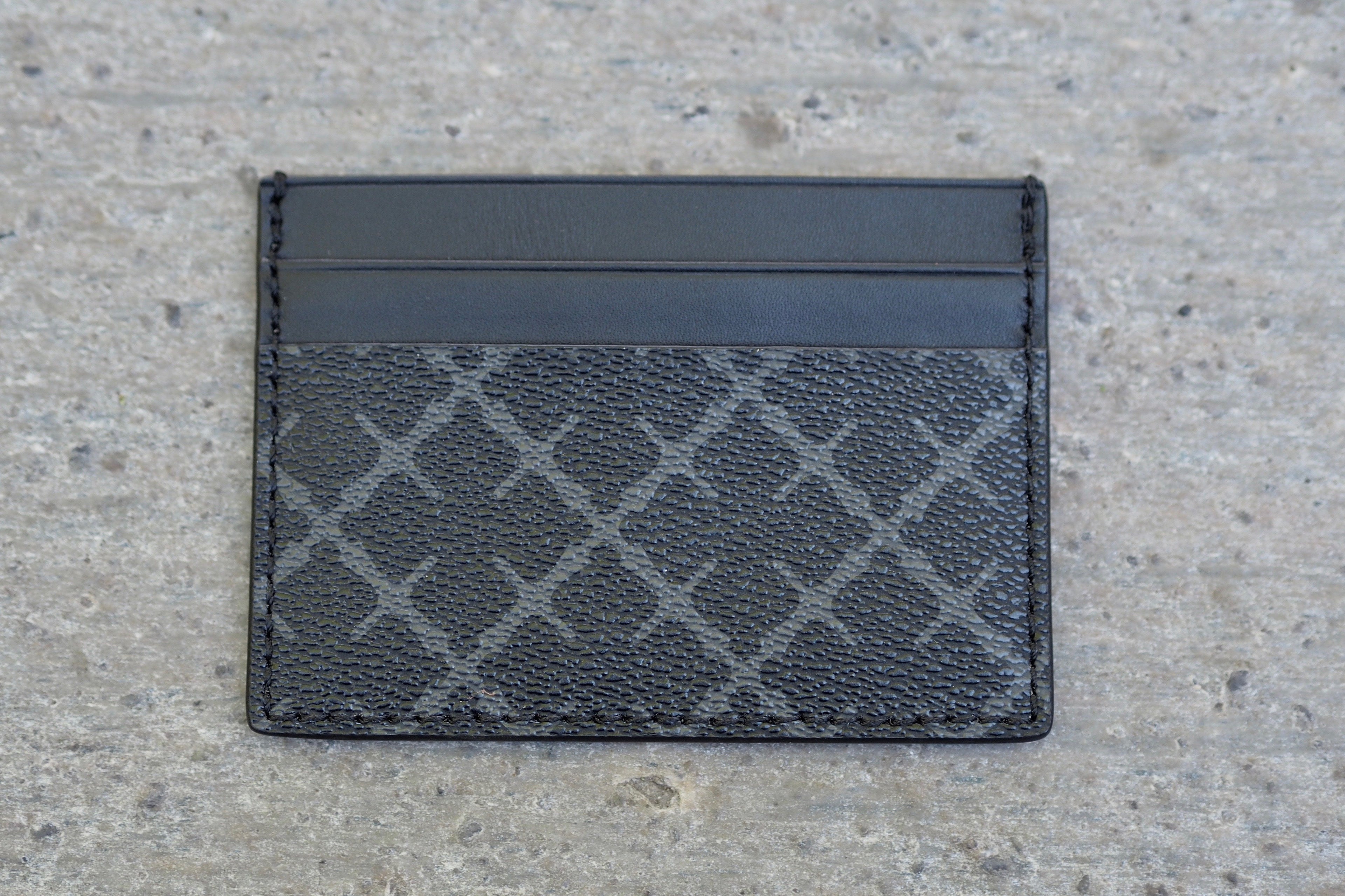 By Malene Birger Elia Card kortholder i koksgrå, laget av 100% polyvinylklorid, med Signature Flower-print og plass til flere kort.