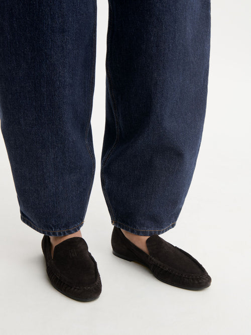 ELISA loafers fra By Malene Birger i fargen mørkebrun, laget i myk semsket skinn. Smal passform, rund tå og preget monogram over vristen.