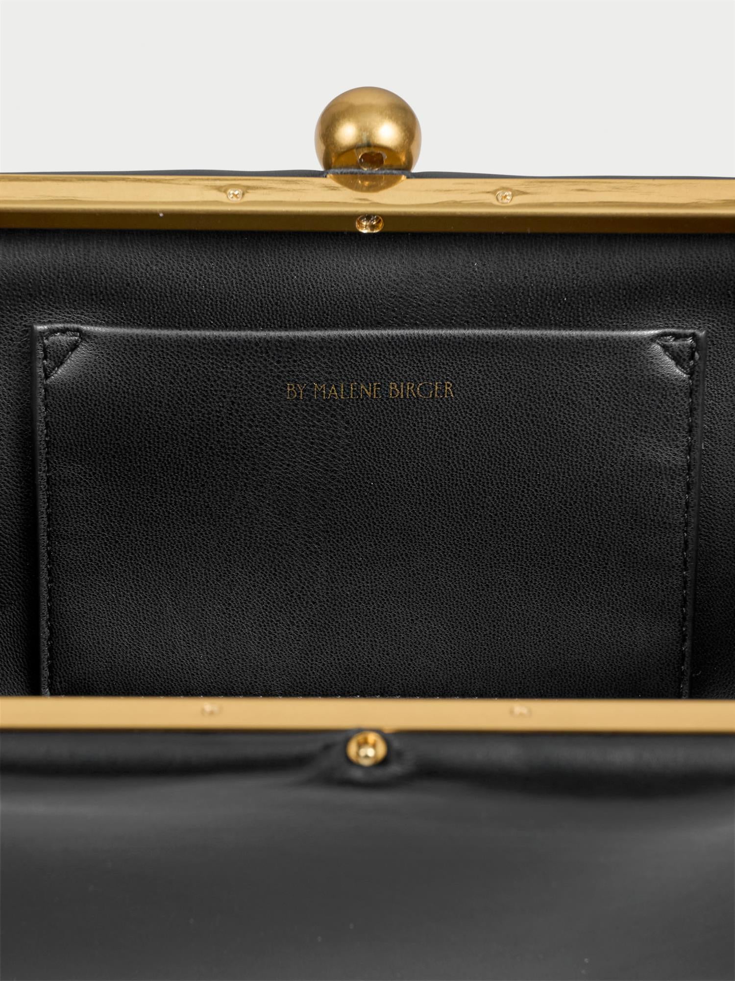ELLON NAPPA veske fra By Malene Birger i fargen sort, laget i 100% kuskinn. Metallstropp, avtagbar skulderreim, innvendig lomme og "Kiss-Lock"-lukking.