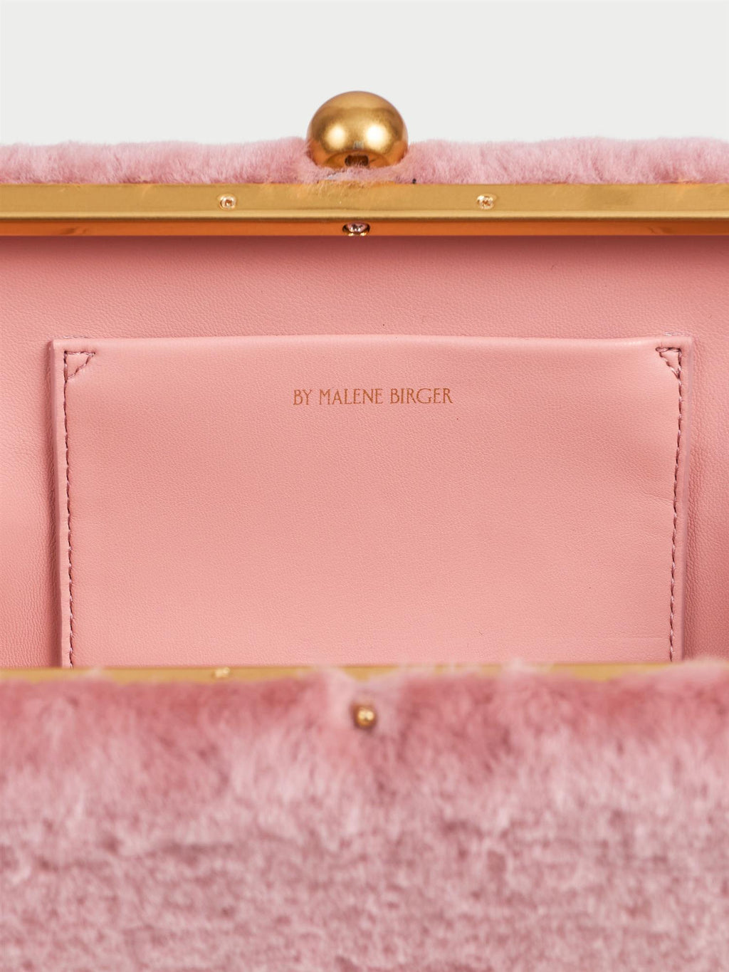 ELLON SHEARLING veske fra By Malene Birger i fargen rosa, laget i farget saueskinn. Metallstropp, avtagbar skulderreim, innvendig lomme og "Kiss-Lock"-lukking.