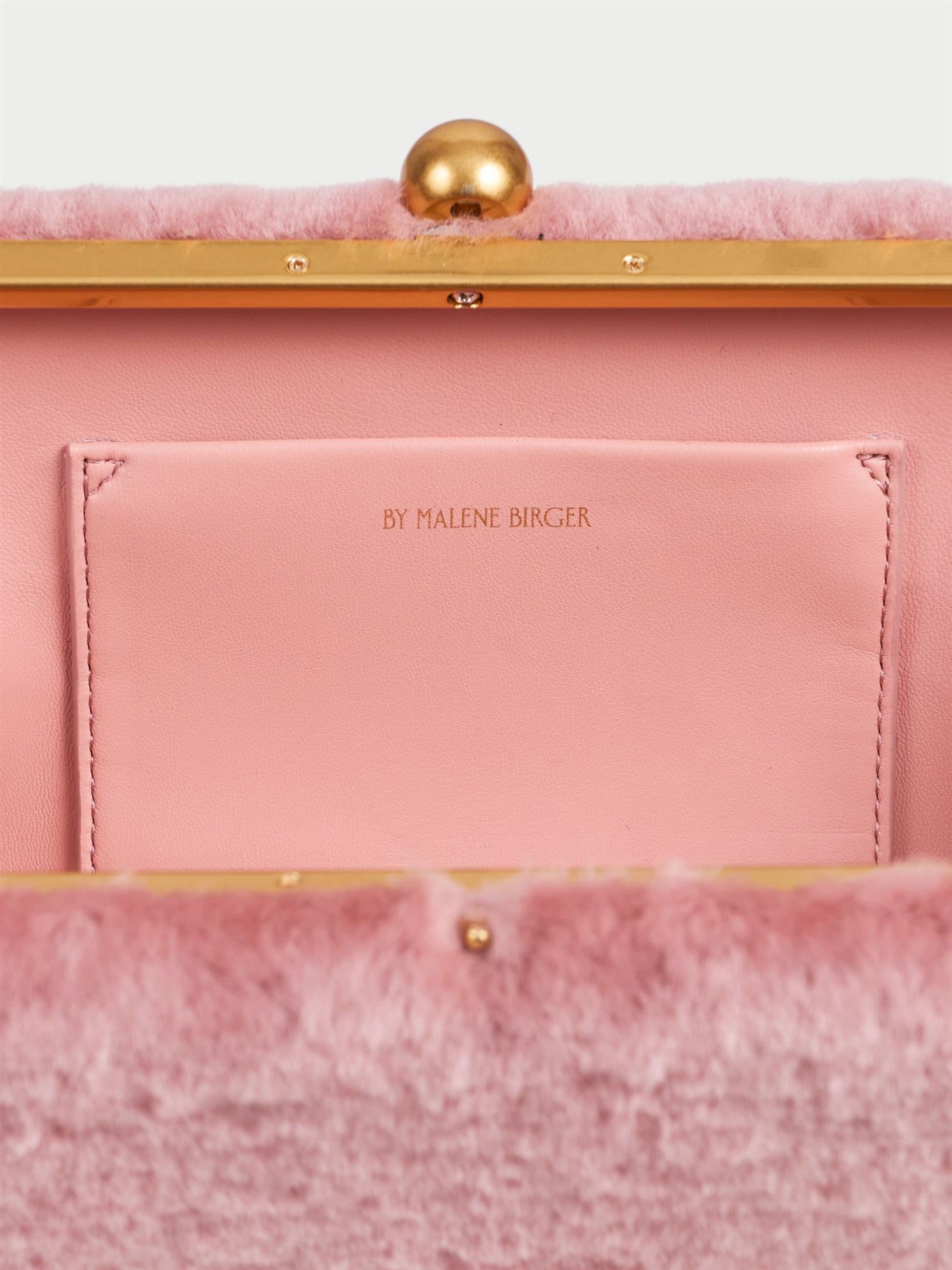 ELLON SHEARLING veske fra By Malene Birger i fargen rosa, laget i farget saueskinn. Metallstropp, avtagbar skulderreim, innvendig lomme og "Kiss-Lock"-lukking.