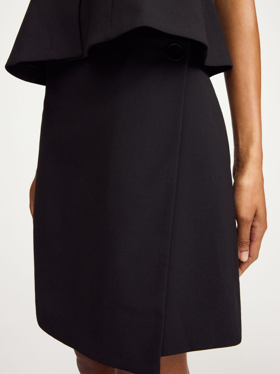 By Malene Birger Esma omslagsskjørt i sort, laget av resirkulert polyester, viskose og elastan, med en knapp i siden.