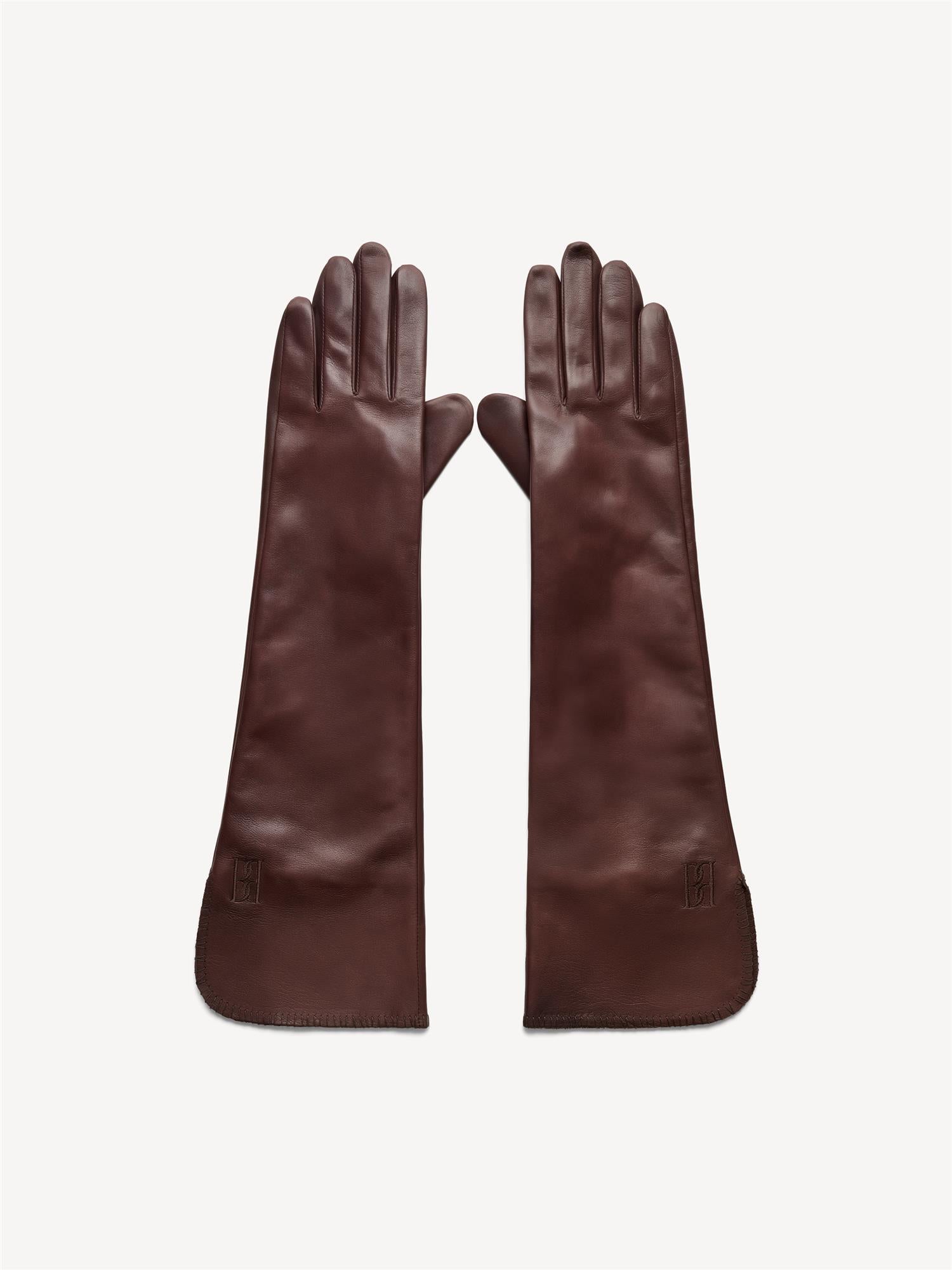 By Malene Birger Gemi lange skinnhansker i mørkebrun, laget av 100% saueskinn med brodert monogram.