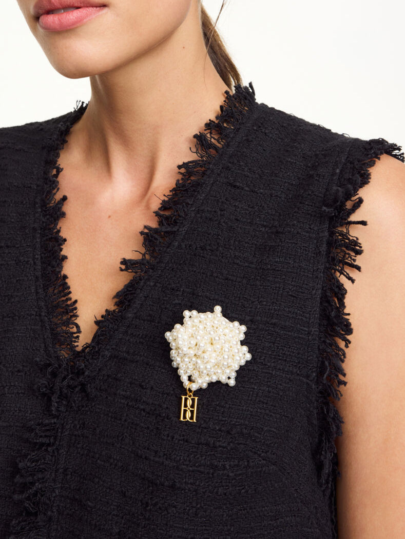 By Malene Birger Helea brosje i hvit, laget av plastikk med falske perler, et monogram-anheng og nålukking.