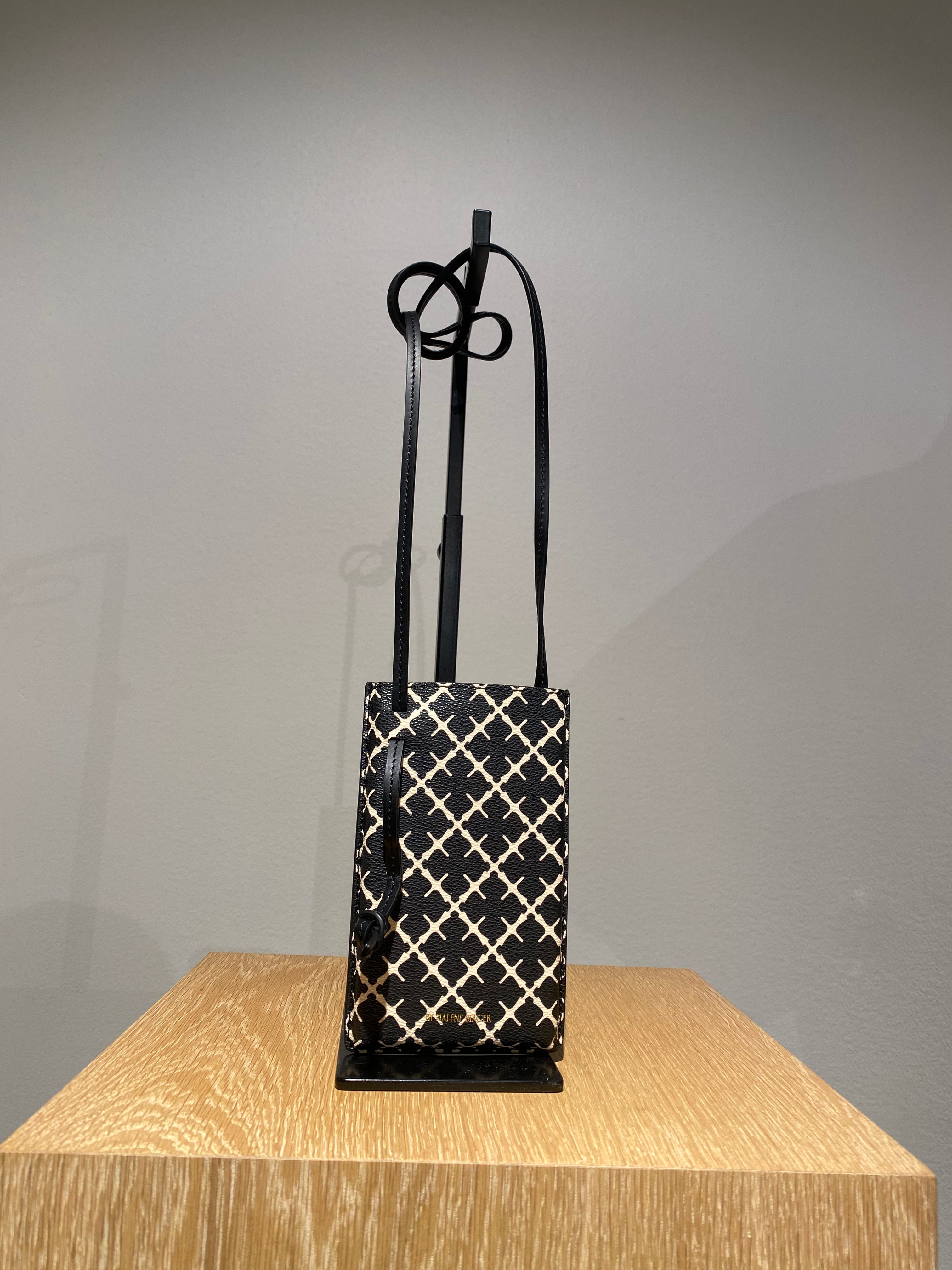 By Malene Birger Ivy mobilveske i sort polyvinyl chloride, med Signature Flower-mønster.