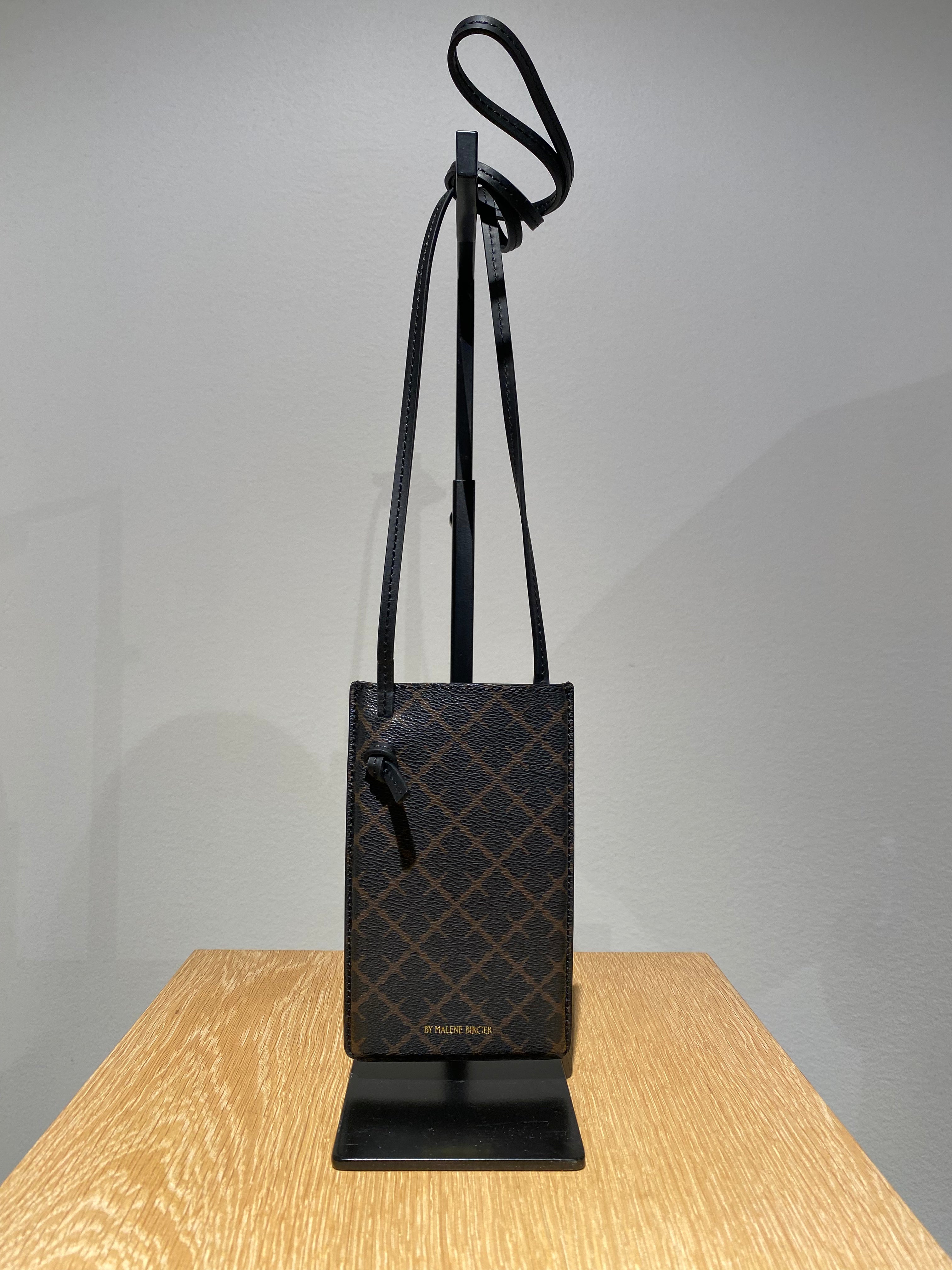 By Malene Birger Ivy Phone mobilveske i mørkebrun, laget av 100% polyvinylklorid med Signature Flower-print.