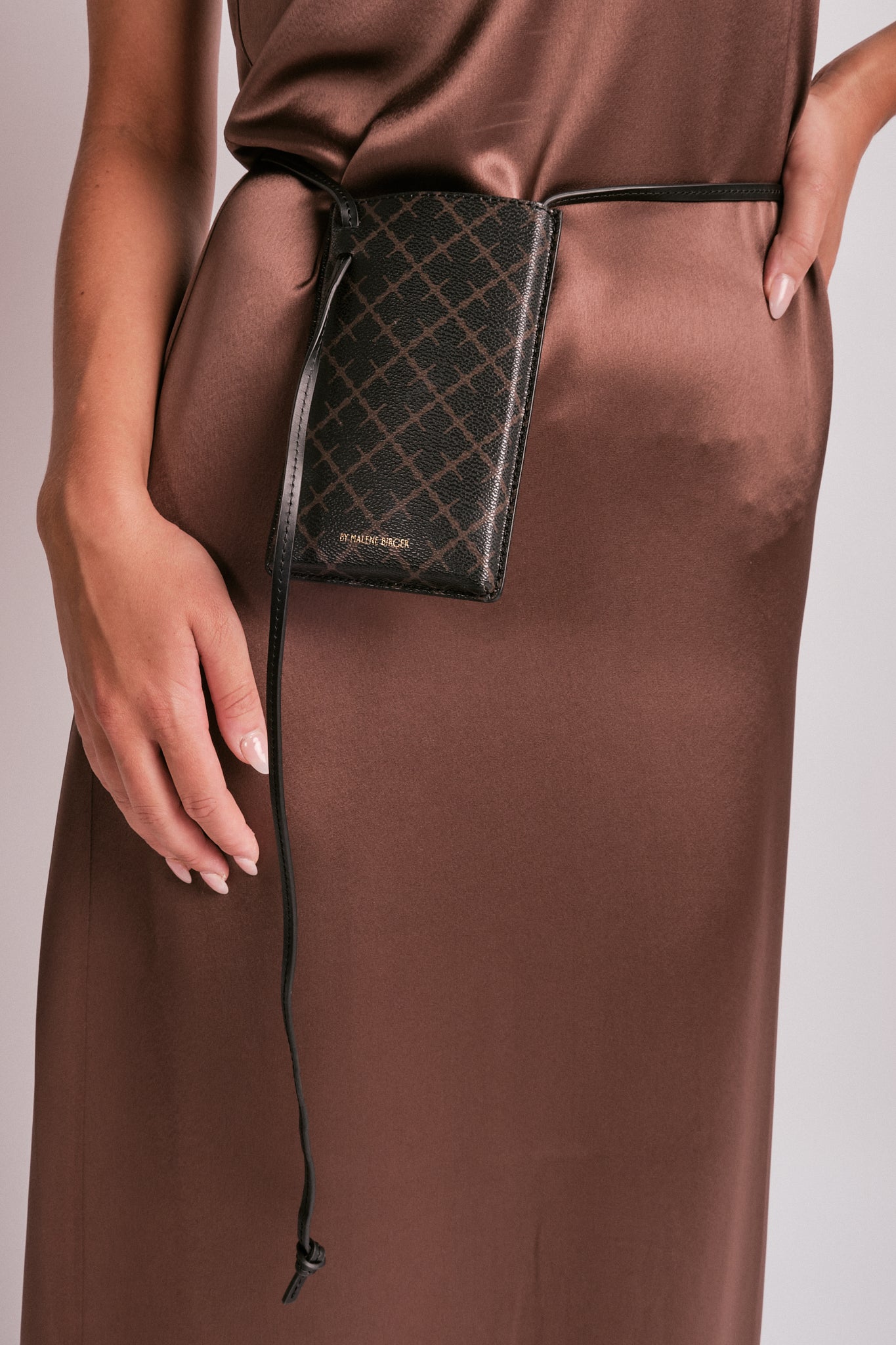 By Malene Birger Ivy Phone mobilveske i mørkebrun, laget av 100% polyvinylklorid med Signature Flower-print.