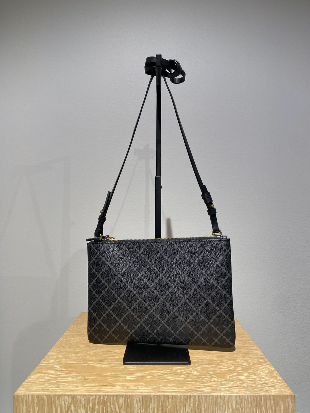 By Malene Birger Ivy veske i mørkegrå firkantet form, med Signature Flower-mønster og avtagbar stropp.