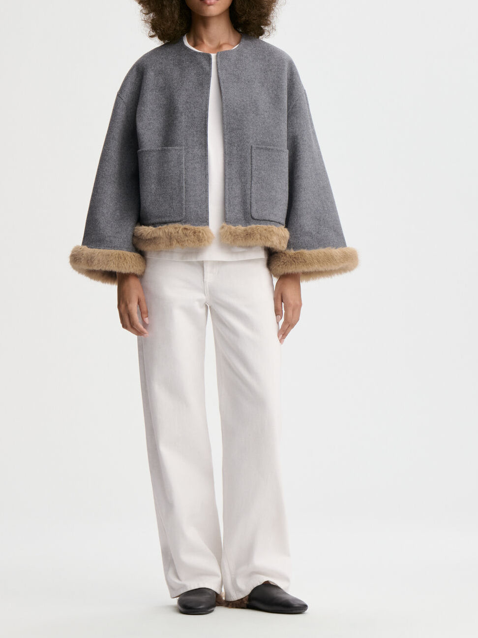 JACQUIELINE jakke fra By Malene Birger i fargen grå, laget i 100% ull med faux fur-avslutning på ermene og kroppen. U-foret med store lommer i front.
