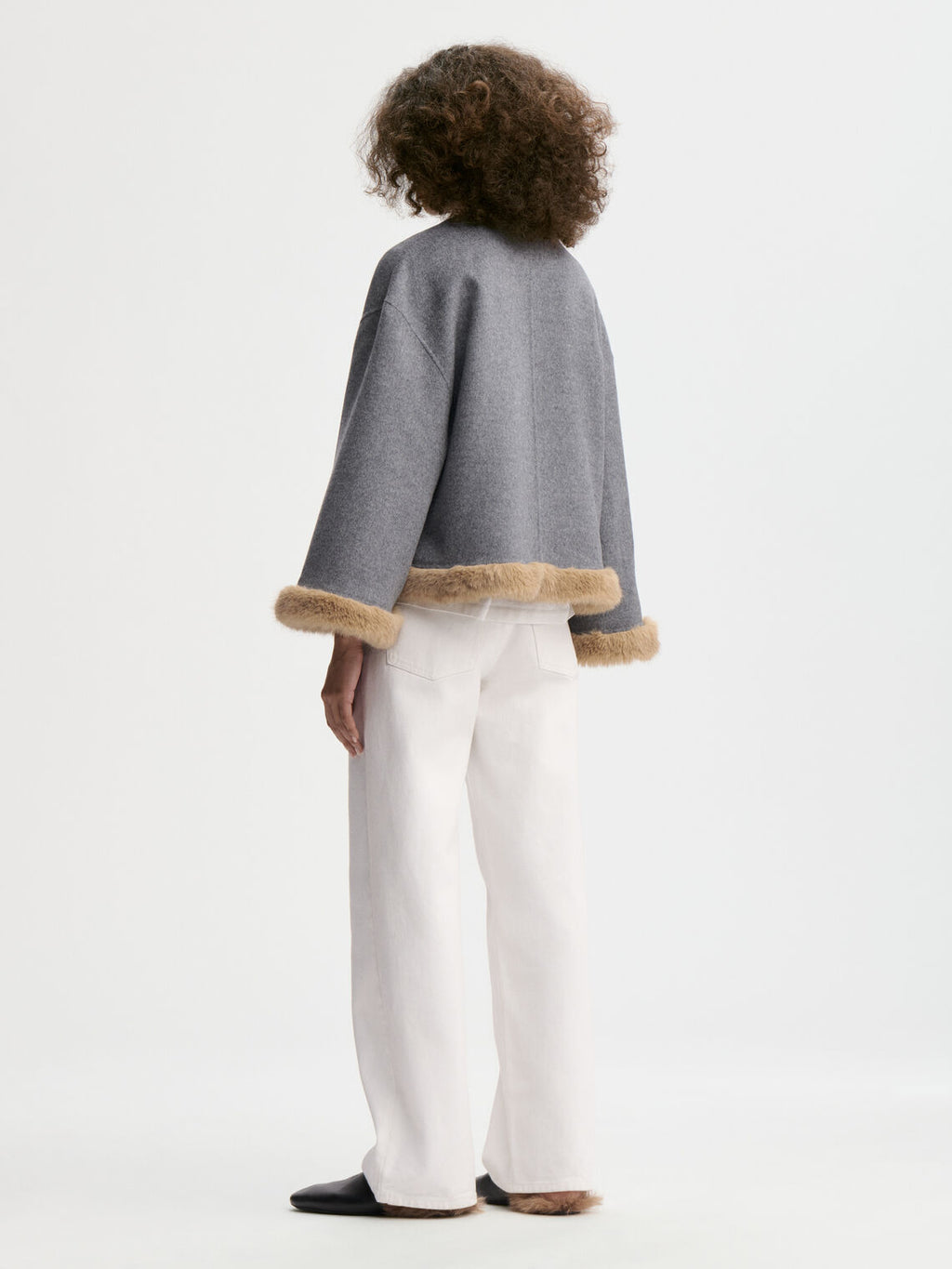 JACQUIELINE jakke fra By Malene Birger i fargen grå, laget i 100% ull med faux fur-avslutning på ermene og kroppen. U-foret med store lommer i front.