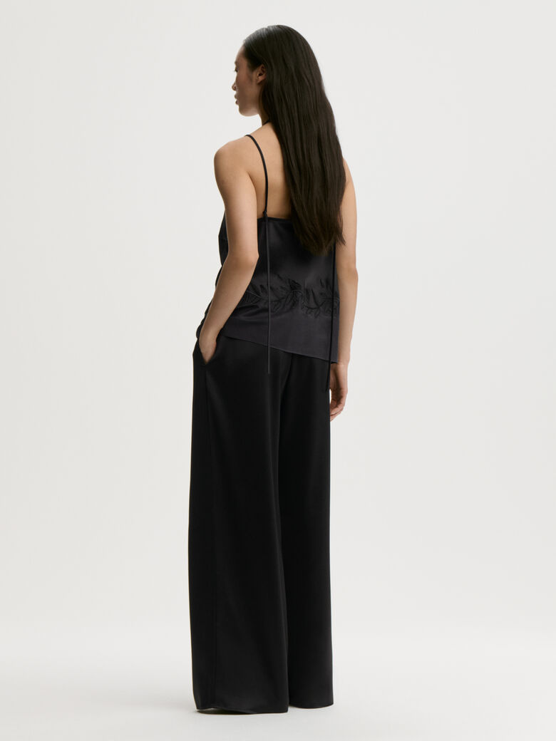 JANINA singlet fra By Malene Birger i fargen sort, laget i 76% acetat og 24% polyester sateng. Rett utringning, gjennomsiktig parti nederst med brodert bord og justerbare stropper.