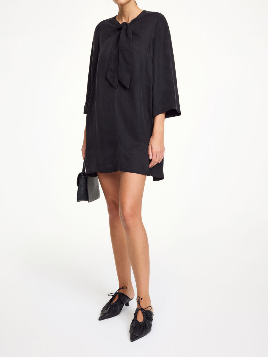 By Malene Birger Javea kjole i sort, med knyting i halsen, laget av en blanding av cupro og viskose.